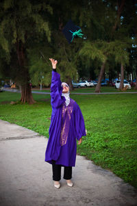 Full length of woman with arms raised against trees