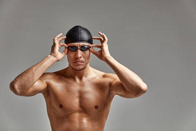 Portrait of shirtless man wearing hat against black background