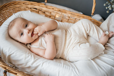 Baby lies in a wicker basket gray background willow eco style