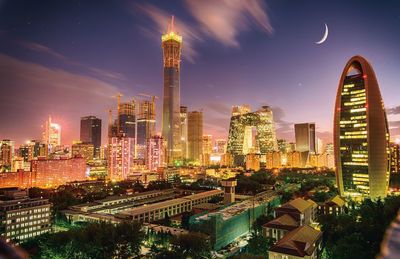 Illuminated cityscape against sky at night