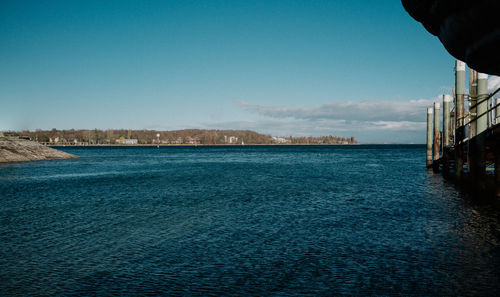 Scenic view of sea by buildings against clear blue sky