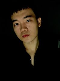 Close-up portrait of young woman against black background