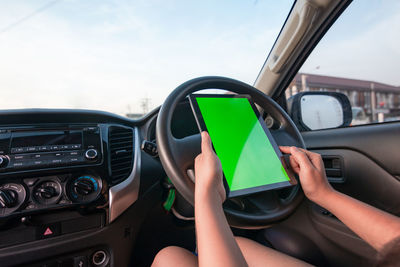 Cropped image of woman with green digital tablet sitting in car