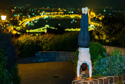 Man doing handstand in city at night