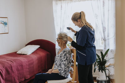 Home caretaker doing senior woman's hair