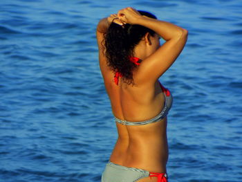 Woman in bikini standing against sea