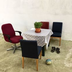 Empty chairs and table against wall