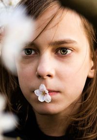 Close-up portrait of a kid with sakura petal in mouth