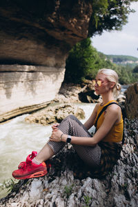 Woman sitting on rock at river