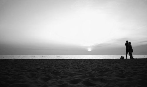 Rear view of silhouette man standing on beach against sky