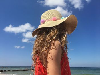 Woman wearing hat at beach against sky