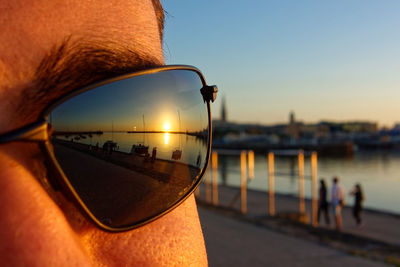 Close-up of man with sunglasses against sky during sunset