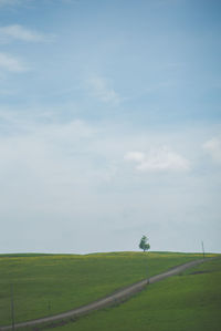 Country road on field against sky