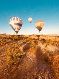 Hot air balloons flying over landscape against sky