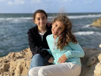 Portrait of two young girls sitting at beach