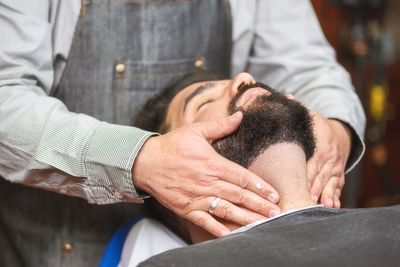 Midsection of barber giving massage to customer in salon