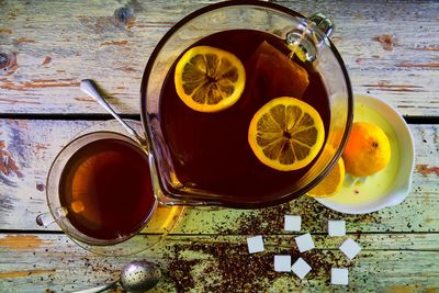 Black tea, a cup of black tea, manual squeezer with lemons. a jug of black tea and cubes of sugar