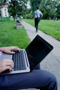 Midsection of man using laptop in park