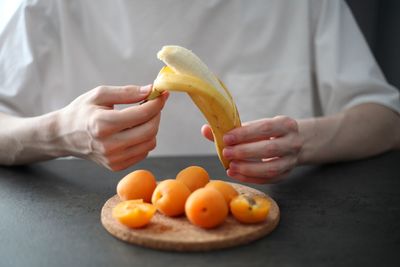 Midsection of man holding orange on table