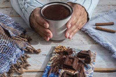 High angle view of man holding coffee cup on table