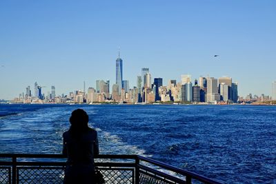 Rear view of woman sitting on railing