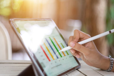 Cropped hand of businesswoman using digital tablet on desk