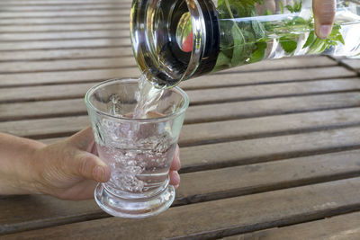 Person holding glass of water on table