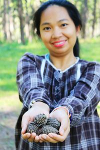 Portrait of smiling woman holding dry pinecones