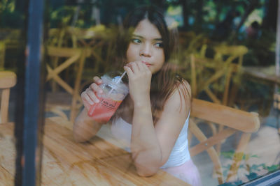 Woman having drink while looking through window