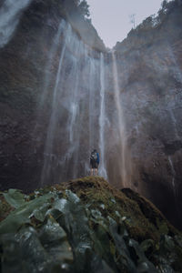 Low angle view of waterfall on rocks against mountain