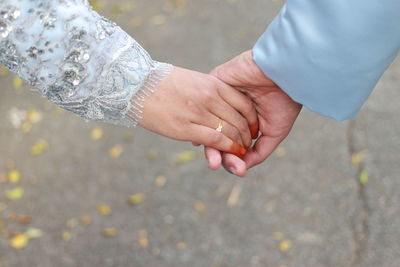 Cropped hand of groom holding bride hand