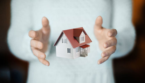 Midsection of man with model house