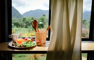 Fruits by window in plate on table at home