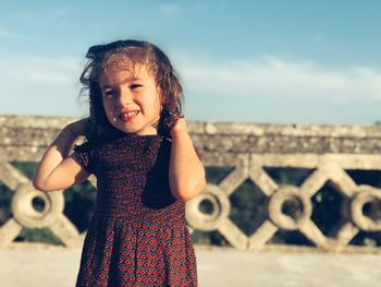 Smiling cute girl standing against railing