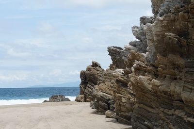 Rock formations on beach against sky