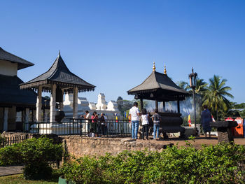 People in front of building against clear blue sky