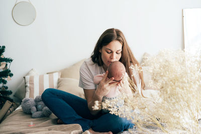 Full length of mother embracing baby at home