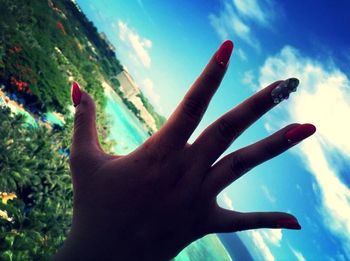 Cropped image of hand against blue sky