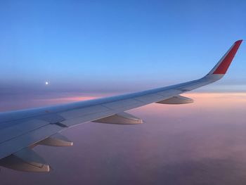 Airplane wing against sky during sunset