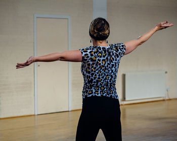 Woman with arms outstretched dancing on hardwood floor at studio