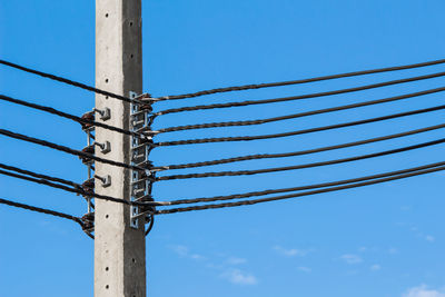 Low angle view of electricity pylon against blue sky