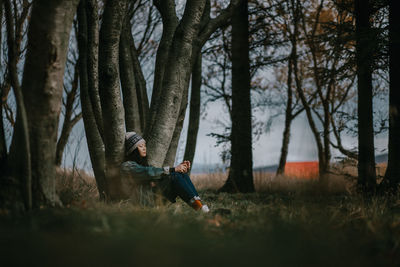 Man sitting on tree trunk in forest