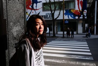 Young woman with umbrella on street in city