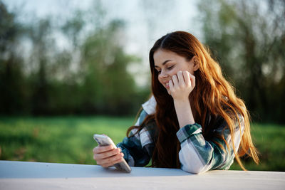 Young woman using mobile phone while sitting outdoors