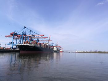 Cranes at commercial dock against sky