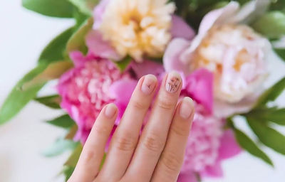 Close-up of nail art against flower outdoors