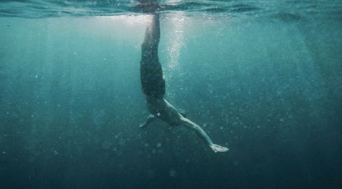 Shirtless man swimming in sea