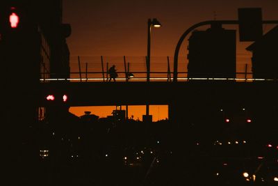 Silhouette people on illuminated street against sky at night