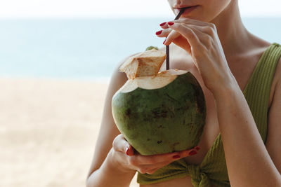 The girl with the coconut on the beach. girl drinks coconut milk on the beach