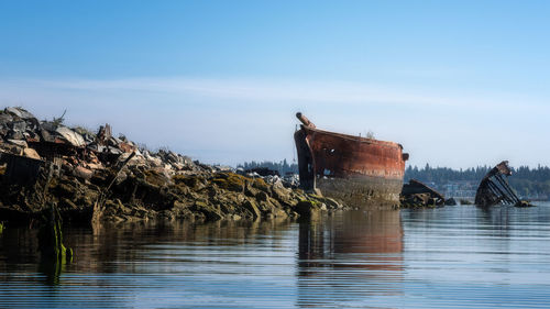 Abandoned boat in sea against sky